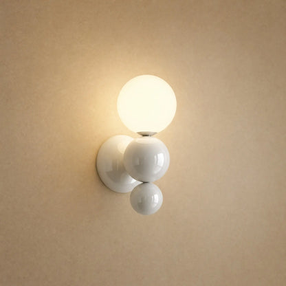 Applique murale boule blanche, grappe de trois billes laquées et globe opale allumé