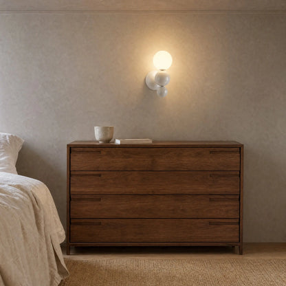 Applique murale boule blanche allumée au-dessus d'une commode en noyer dans une chambre