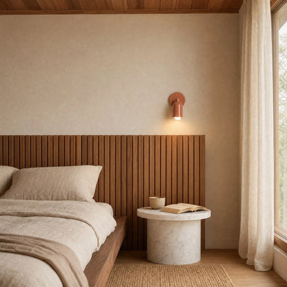 Applique murale Nolvina rose corail allumée au-dessus d'une tête de lit en bois dans une chambre