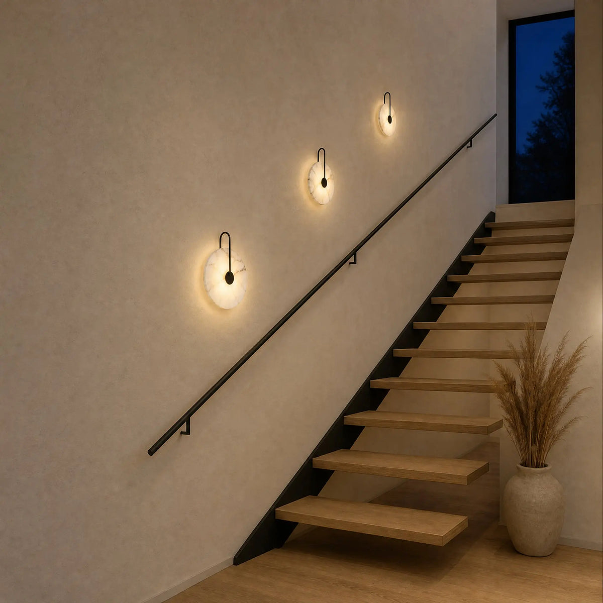 Trois appliques murales en marbre Ø 25, 20 et 16 cm allumées le long d'une montée d'escalier | Delvanie