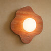 Applique murale terracotta en travertin, format Corolle 29 x 28 cm, globe de verre dépoli allumé