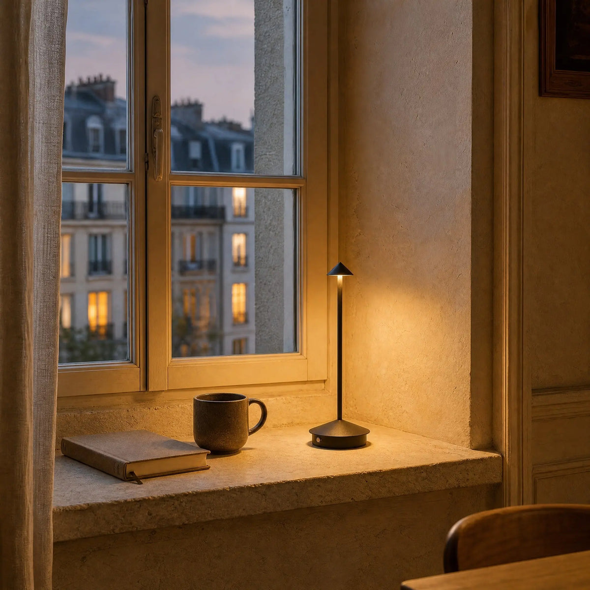 Lampe de table sans fil noire allumee sur un appui de fenetre au crepuscule