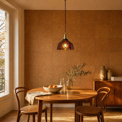 Lampe vitrail Mosaira allumée au-dessus d'une table ronde en teck, mur de liège naturel
