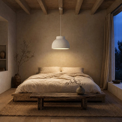 Lustre Nivoya allumé au-dessus du lit dans une chambre wabi-sabi au crépuscule