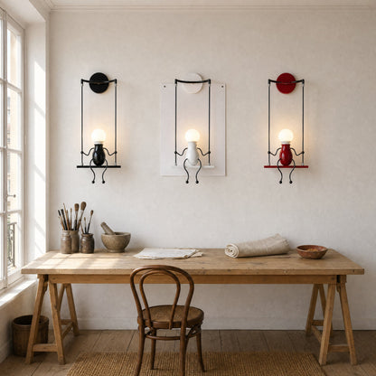 Trois appliques murales Girotta noire, blanche et rouge alignées au-dessus d'une table d'atelier | Delvanie