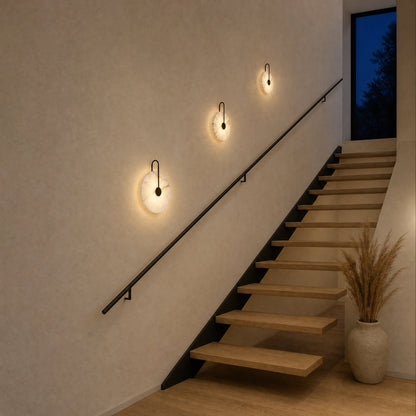 Trois appliques murales en marbre Ø 25, 20 et 16 cm allumées le long d'une montée d'escalier | Delvanie