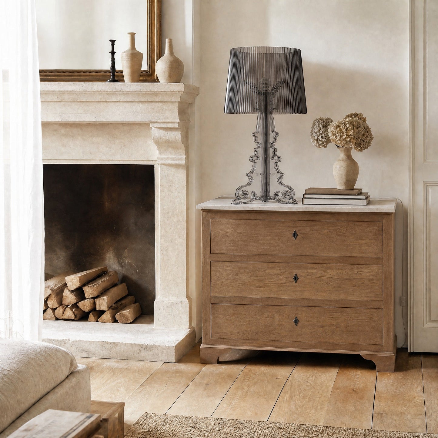 Lampe baroque Rivento en acrylique noir fumé posée sur une commode à plateau de marbre près d'une cheminée en pierre | Delvanie