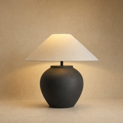 Lampe céramique à poser, jarre noire mate et large abat-jour écru, allumée | Delvanie