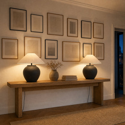 Paire de lampes céramique noires allumées sur une console sous un mur de cadres | Delvanie