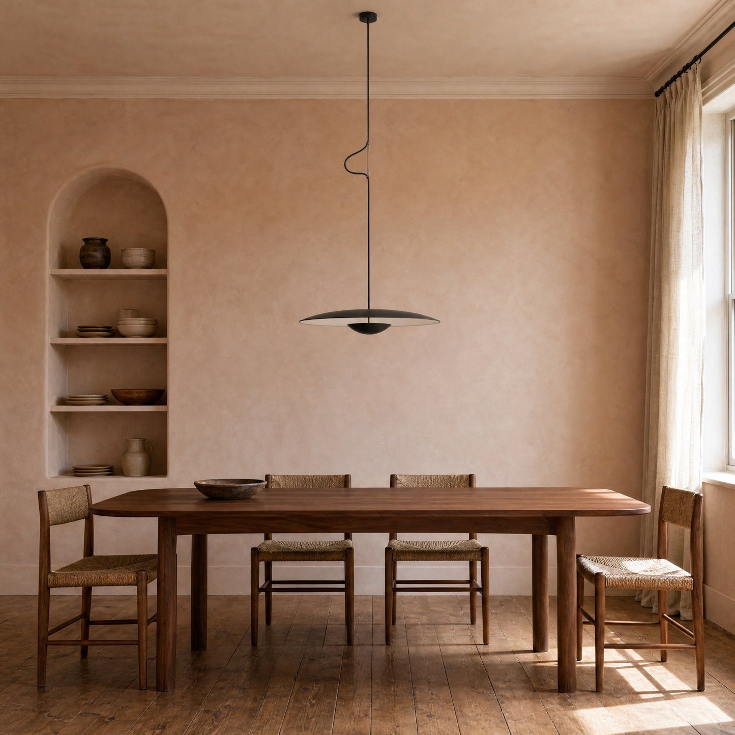 Suspension noire au-dessus d'une table de noyer dans une salle à manger aux murs ocre | Delvanie